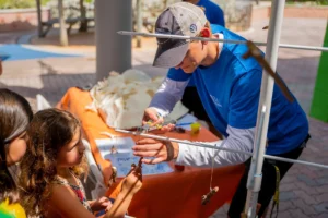 CRF team member helps a young girl attach coral fragments to a demonstration coral tree at an outreach event.