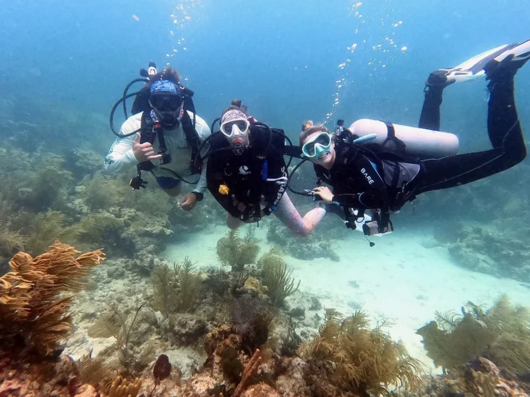 Three scuba divers posing over reef