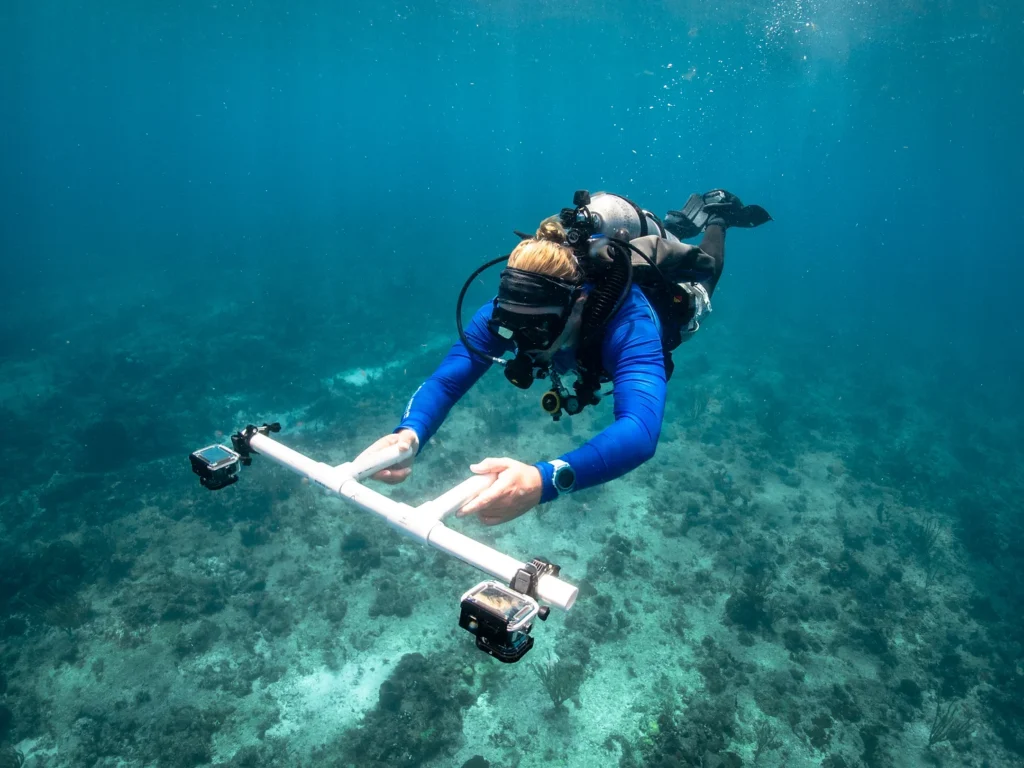 Diver swimming in blue CRF shirt holding camera rig