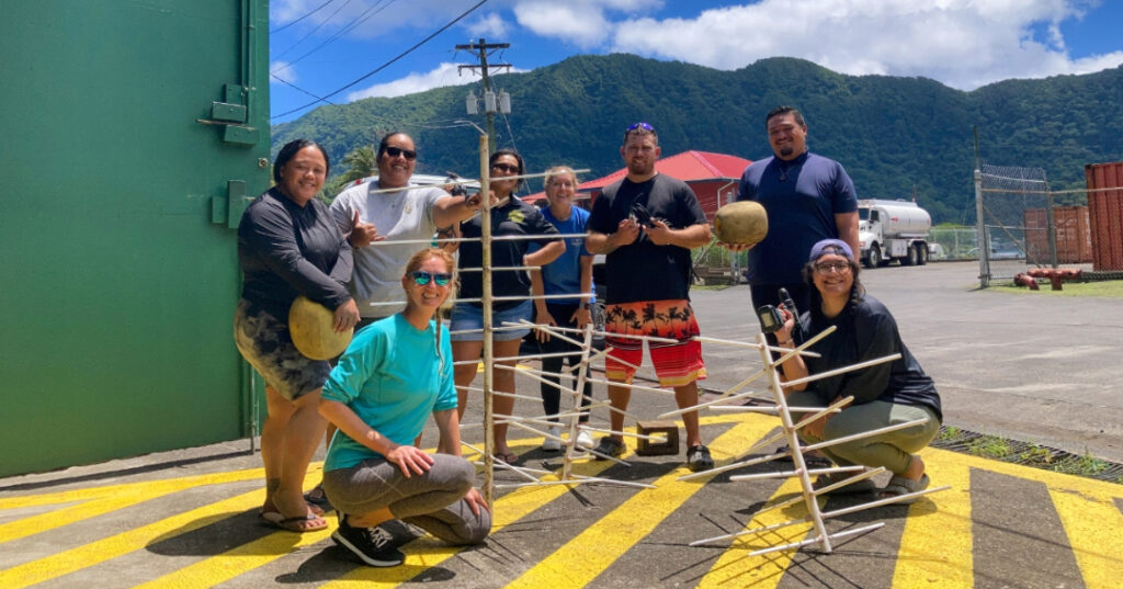 A group of smiling participants stands around a newly built Coral Tree™ frame during the American Samoa learning exchange.
